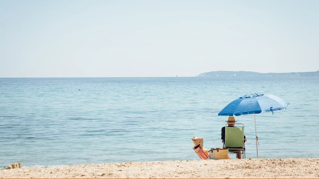 Ein Mann am Strand sitzt unter einem Sonnenschirm