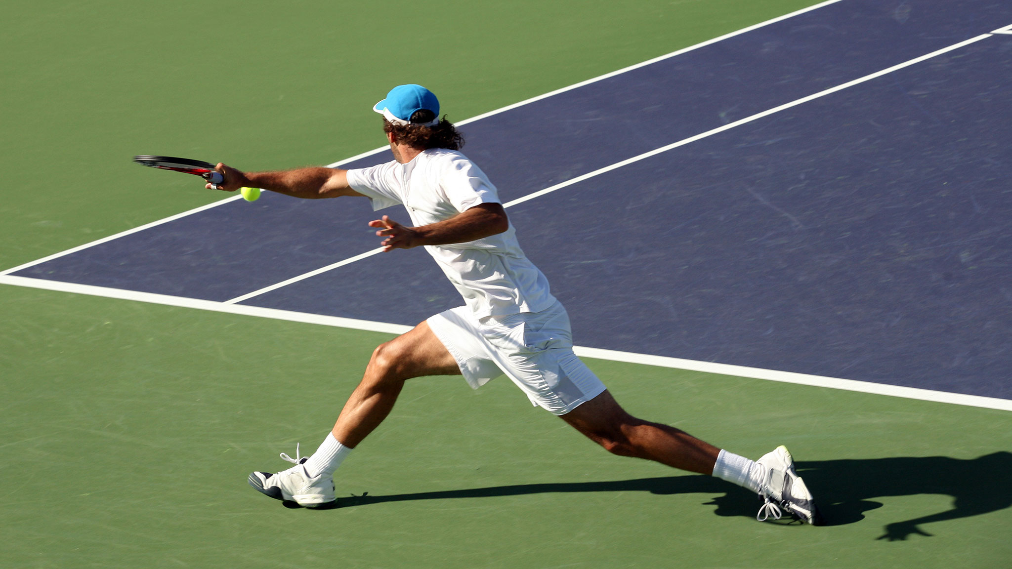 Tennisspieler im Seitenschritt – sportliche Belastung ist eine mögliche Ursachen für Knieschmerzen