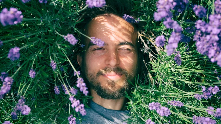 Reisen mit Allergien ist schwierig. Aber dieser junge Mann konnte seine Allergie überwinden, und jetzt liegt auf eine Blumenwiese und genießt den Frühling in der Natur