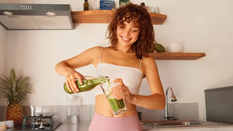 Eine junge Frau gönnt sich einen grünen Smoothie für einen gesunden Darm und einen besser funktionierenden Stoffwechsel