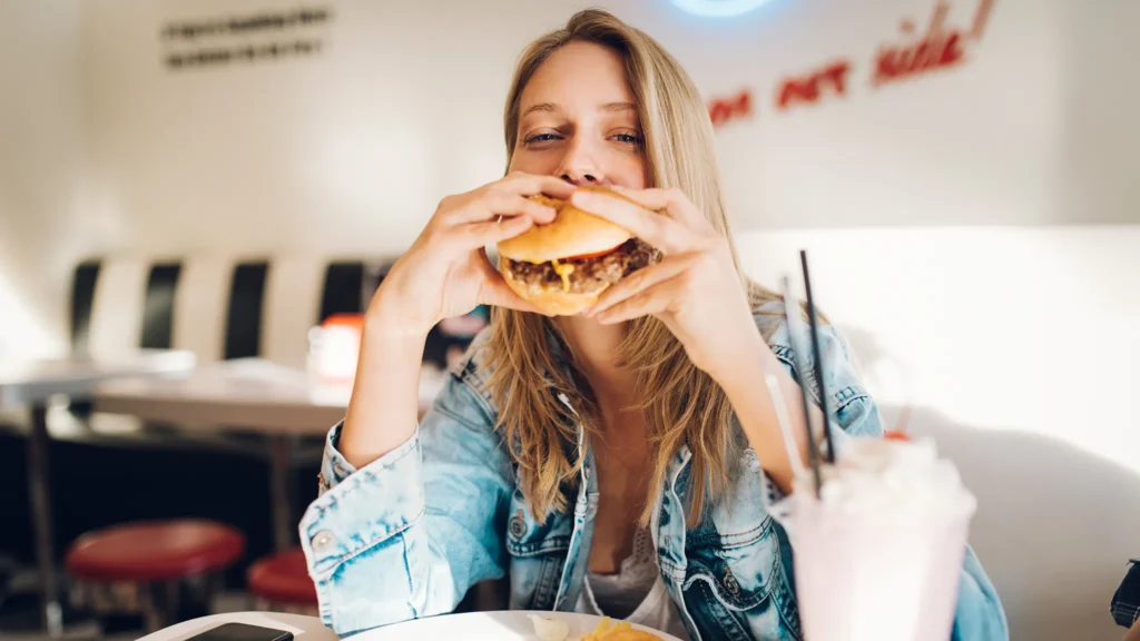 Eine Frau isst einen Burger - er scheint ihr sehr zu schmecken - Jo-Jo-Effekt